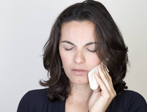 Woman holding cold compress to cheek