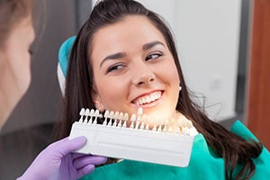 A dentist comparing dental shades to a patient’s smile.